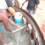 Workers carrying out curved RCC formwork concreting with steel shuttering and reinforcement at a construction site